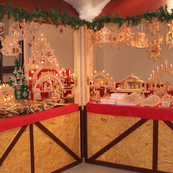 Ein Weihnachtsmarktstand mit weihnachtslicher Holzdekoration wie Schwibbögen und Krippen