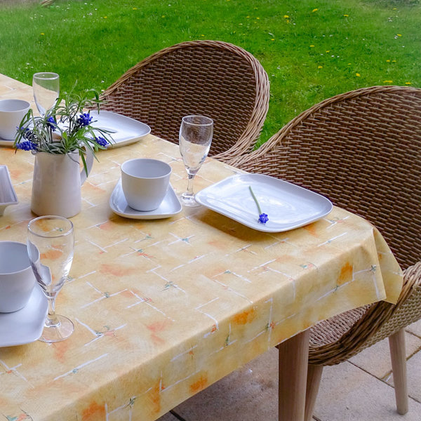Gartentisch zum Kaffee gedeckt im blühenden Garten mit einer schönen Wachstuch Tischdecke aus dem Haushaltsbedarfshop